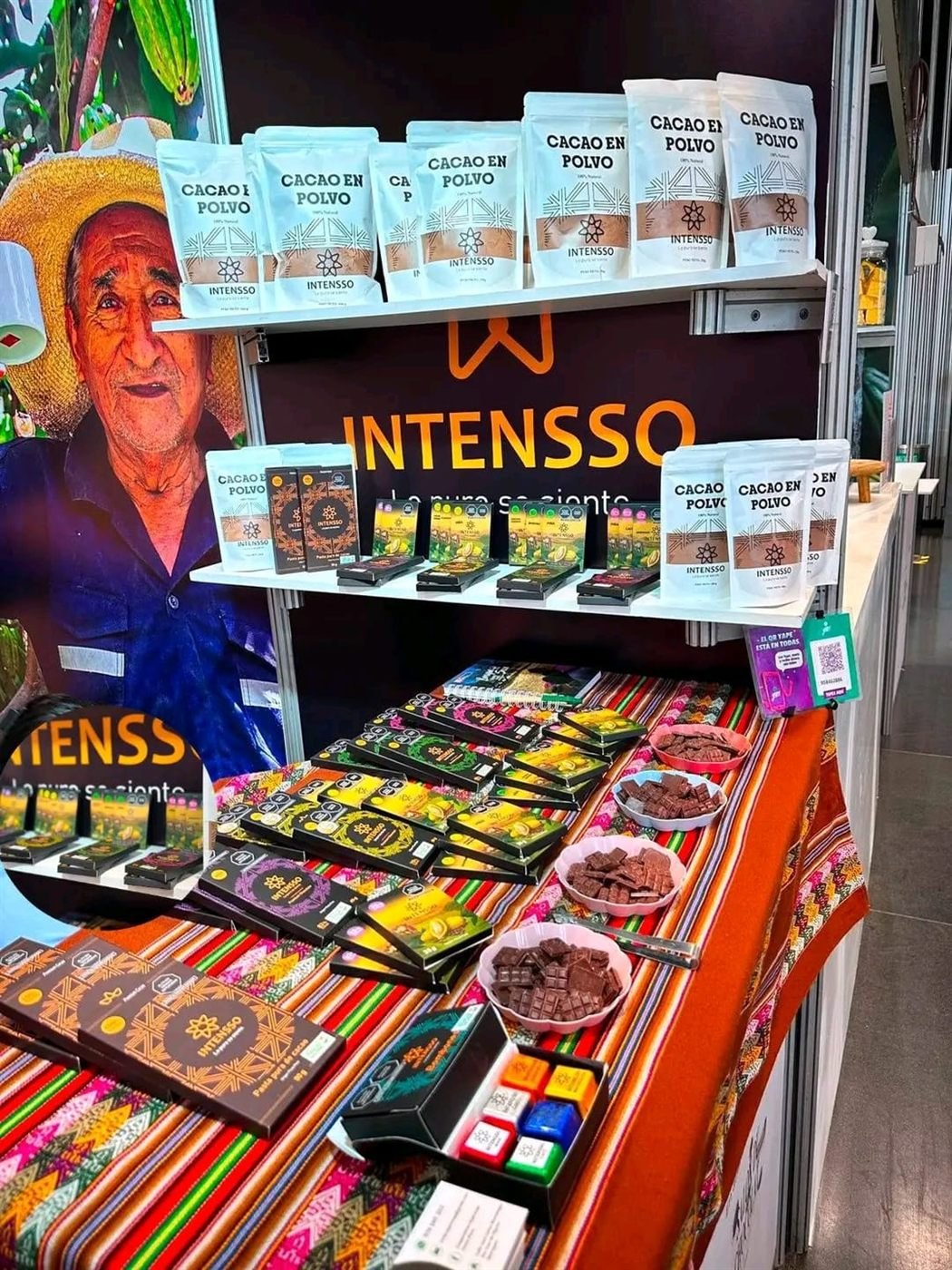 Stand de INTENSSO en una feria, con anaqueles de productos derivados de cacao